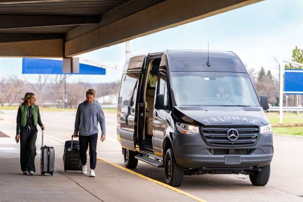 Photo of Two people walking outside near a parked LandJet vehicle.